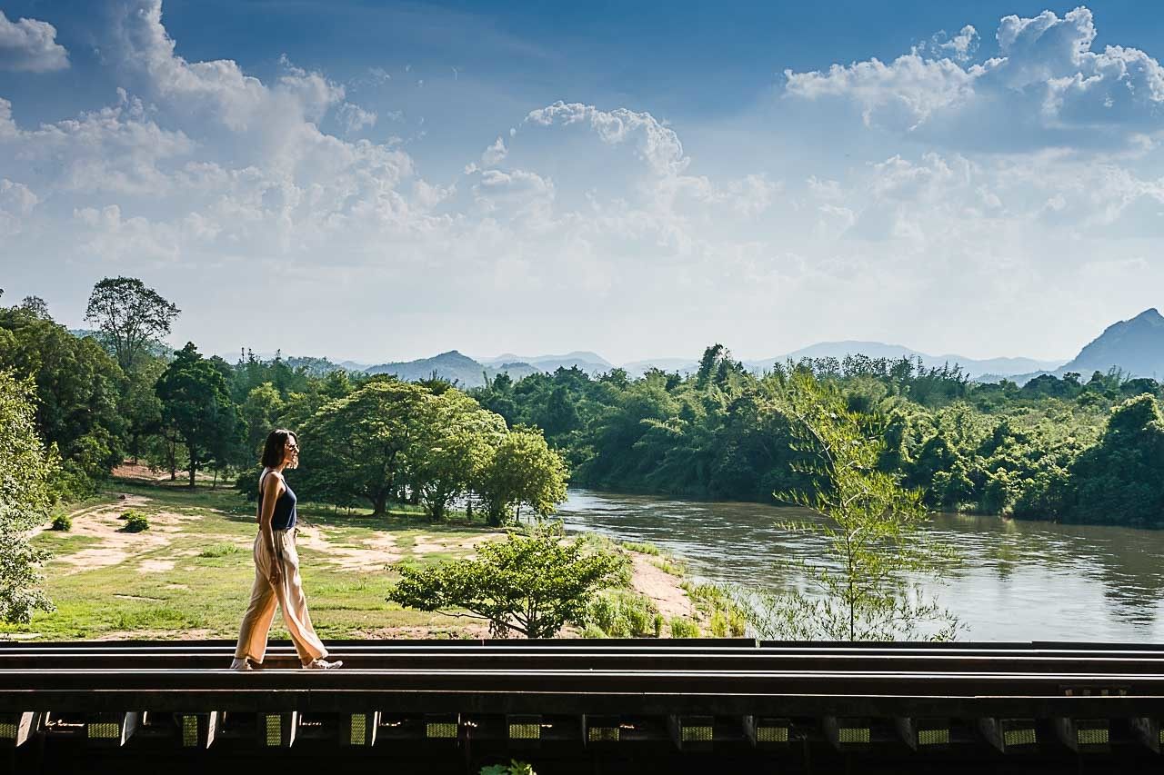A traveler is walking over the track of the Death Railway also known as the Thailand - Burma Railway.