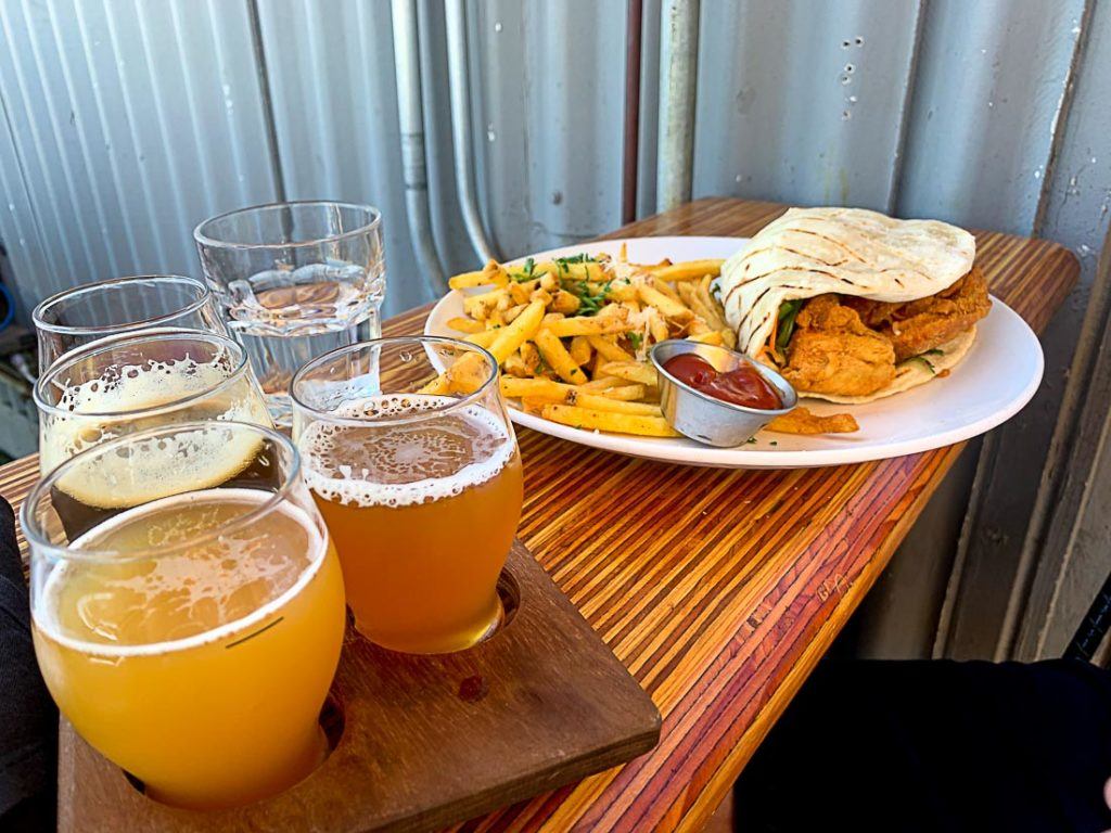 A plate of food and some beers over a table. In this article we talk about all costs of traveling in San Diego, California. Prices of food, drinks, transport, accommodation and attraction that will make your trip budget planning much easier.